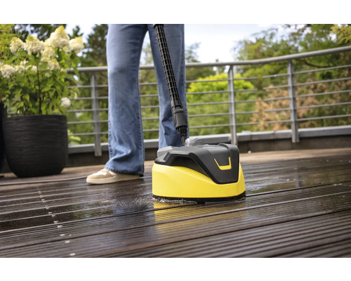 Person reinigt Holzterrasse mit einem Oberflächenreiniger.
