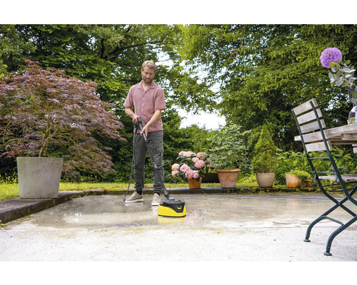 Ein Mann reinigt eine Terrasse mit einem Terrassenreiniger im Garten.