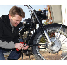 Mann repariert Motorrad mit Schraubendreher