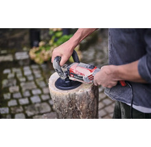 Mann schleift Holzscheit mit einem Einhell Schleifer.