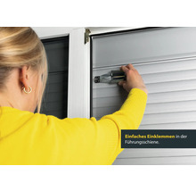 Frau befestigt Rollladen mit Montagehilfe an Führungsschiene