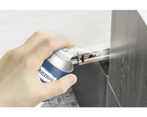 Eine Hand sprüht Gleitspray auf einen Schubladenauszug.
