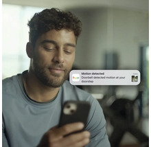 Mann erhält Benachrichtigung über Bewegungserkennung an der Haustür auf seinem Smartphone