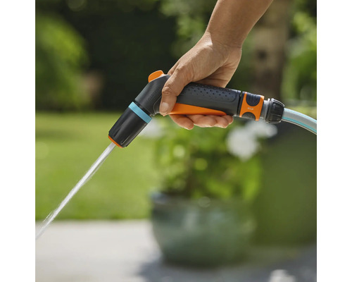 Eine Hand hält eine Gartenspritze, aus der Wasser austritt.