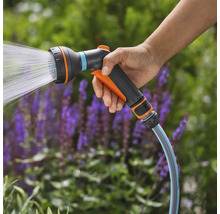 Hand hält Gartenschlauch Spritzpistole mit Wasserstrahl