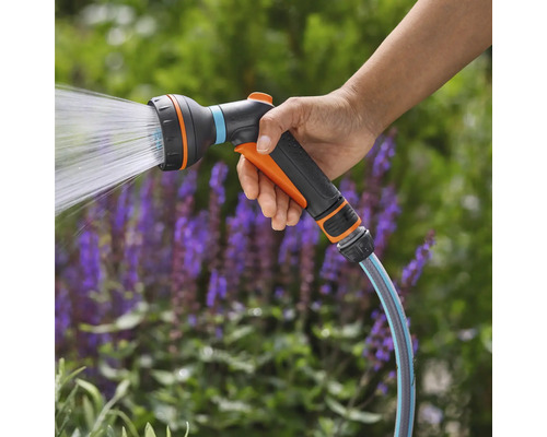 Hand hält Gartenschlauch Spritzpistole mit Wasserstrahl
