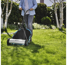 Person schiebt einen Gardena Handrasenmäher über einen Rasen.