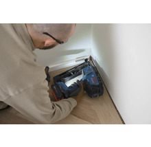 Handwerker befestigt Fußleisten mit einem Akku-Nagler an einer Wand