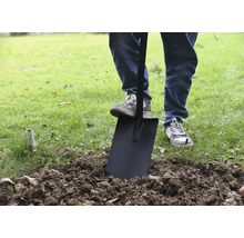 Eine Person benutzt einen Spaten im Garten, um Erde umzugraben.