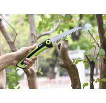 Eine Hand hält eine Astsäge beim Schneiden eines Astes.