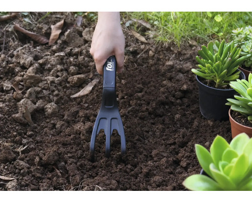 Gartenarbeit mit einer Gartenkralle in der Erde
