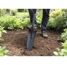 Person benutzt einen Spaten zum Graben im Garten.