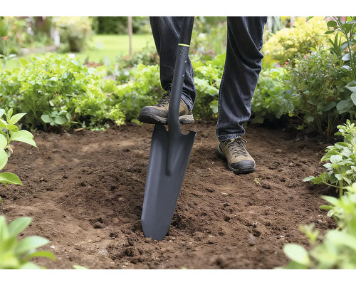 Person benutzt einen Spaten zum Graben im Garten.