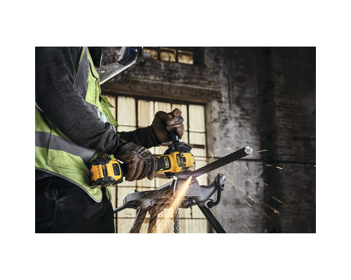 Mann schneidet mit einem Winkelschleifer ein Metallstück in einem Schraubstock. Funken fliegen.