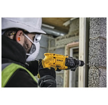 Ein Mann bohrt mit einer DeWalt Bohrmaschine ein Loch in eine Ziegelwand.