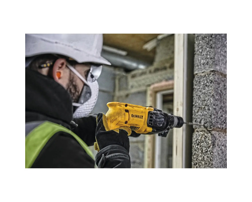 Ein Mann bohrt mit einer DeWalt Bohrmaschine ein Loch in eine Ziegelwand.