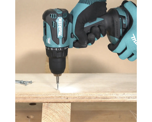 Akkuschrauber beim Eindrehen einer Schraube in ein Holzbrett, bedient von einer Person mit Handschuhen.