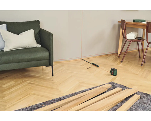 Raumansicht mit Nivellierlaser, Holzleisten und Möbeln für Renovierungsarbeiten