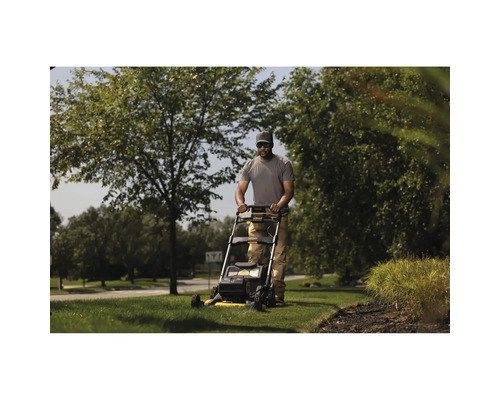 Ein Mann mäht mit einem Rasenmäher den Rasen in einem Garten.