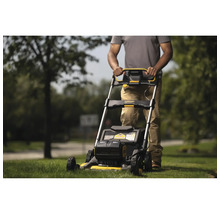 Eine Person bedient einen Rasenmäher im Garten.