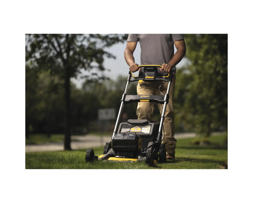 Eine Person bedient einen Rasenmäher im Garten.