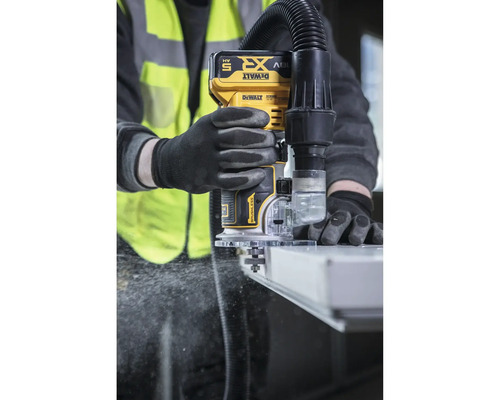 Eine Person bedient eine DeWalt Oberfräse mit Staubabsaugung während der Arbeit.