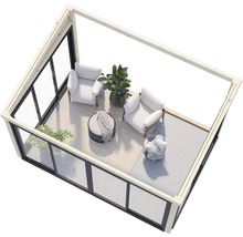 Überblick über eine moderne Gartenlounge mit Sesseln, Tisch und Pflanzen in einem Glashaus