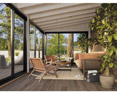 Wohnzimmer mit Terrassendielenboden, Sitzmöbeln und großen Glasfenstern