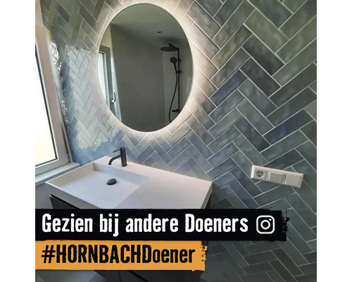 Badezimmer mit Waschbecken, Spiegel und Wandfliesen im Fischgrätmuster