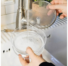 Eine Person wäscht einen Kaltbrühkaffee-Maker unter einem Wasserhahn.