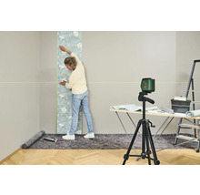 Frau bringt Tapete mit Laserwasserwaage an Wand an