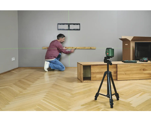 Ein Mann benutzt einen Kreuzlinienlaser, um eine Wasserwaage an einer Wand auszurichten