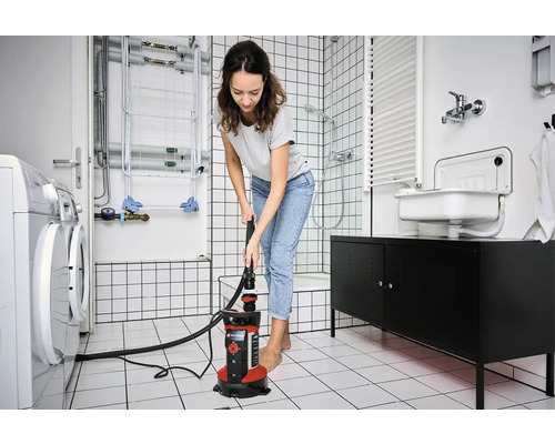 Frau benutzt Tauchpumpe im Badezimmer zur Wasserabsaugung.