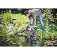 Mann bedient eine Teichpumpe im Gartenteich.