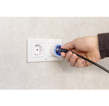 Eine Hand steckt einen Stecker in eine Steckdose.