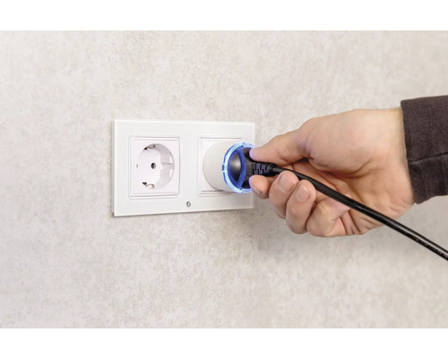 Eine Hand steckt einen Stecker in eine Steckdose.