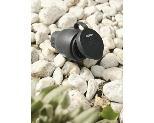 Osram Logo. Gartensteckdose mit geöffnetem Deckel auf Kies.