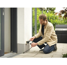 Mann schließt Stecker an Außensteckdose an