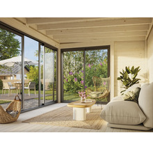 Helles Wohnzimmer mit Sofa, Sessel, Teppich und Blick durch große Fenster auf Gartenmöbel im Außenbereich