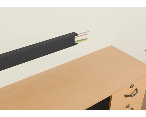 Kabelkanal aus Kunststoff mit Kabeln an einer Wand über einem Schreibtisch