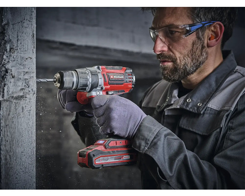 Ein Mann bohrt mit einem Einhell Akku-Bohrschrauber ein Loch in eine Betonwand.