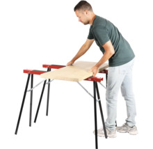 Mann legt Holzbrett auf zwei Arbeitsböcke