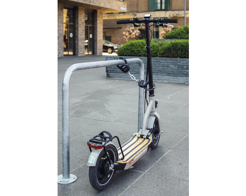Ein E-Scooter ist mit einem Zahlenschloss an einem Fahrradständer gesichert.