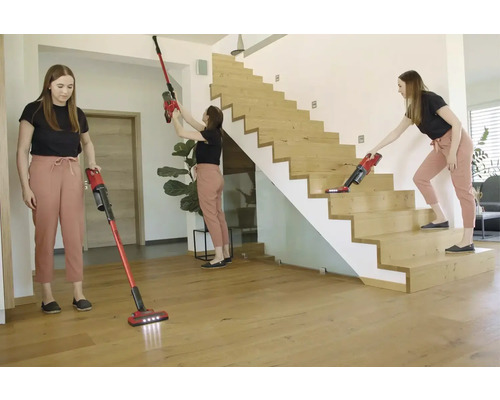 Eine Frau benutzt einen Akku-Staubsauger zum Reinigen von Boden, Decke und Treppe.