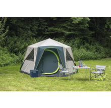 Campingzelt mit Campingmöbeln auf einer Wiese vor Bäumen