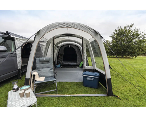 Campingplatz mit aufblasbarem Zelt, Campingmöbeln und Campingausrüstung auf einer Rasenfläche.