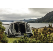Campingplatz mit Zelt, Campingstühlen und Kühlbox am See mit Bergen im Hintergrund