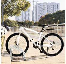 Weißes Fahrrad geparkt auf einem Fahrradständer vor einem Stadtbild.