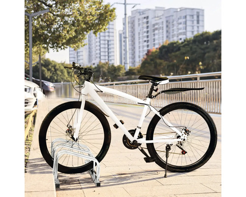 Weißes Fahrrad geparkt auf einem Fahrradständer vor einem Stadtbild.