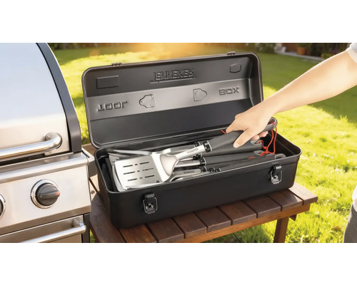 Grillbesteckset in einer schwarzen Aufbewahrungsbox neben einem Grill